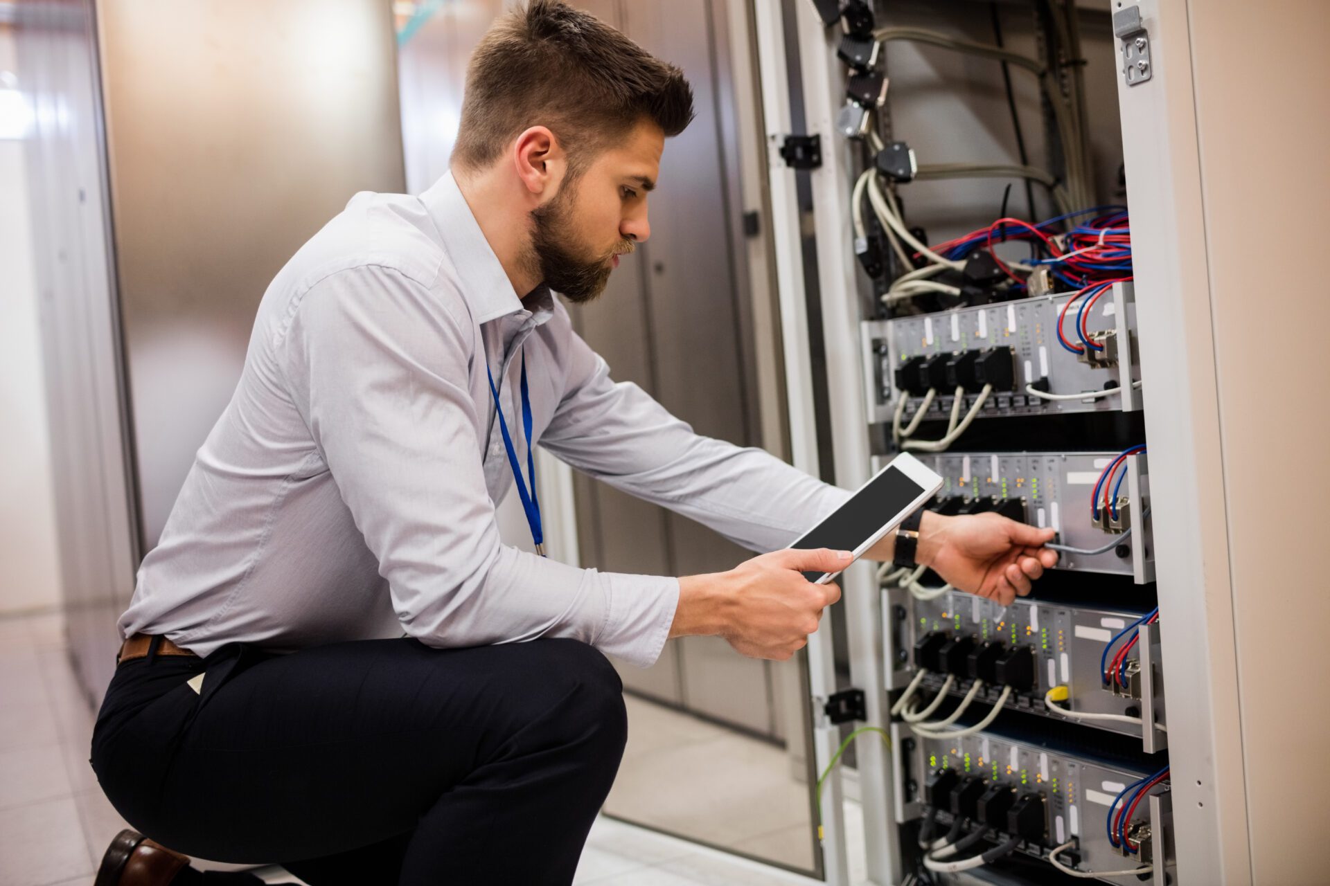 Technician using digital tablet while analyzing server in server room